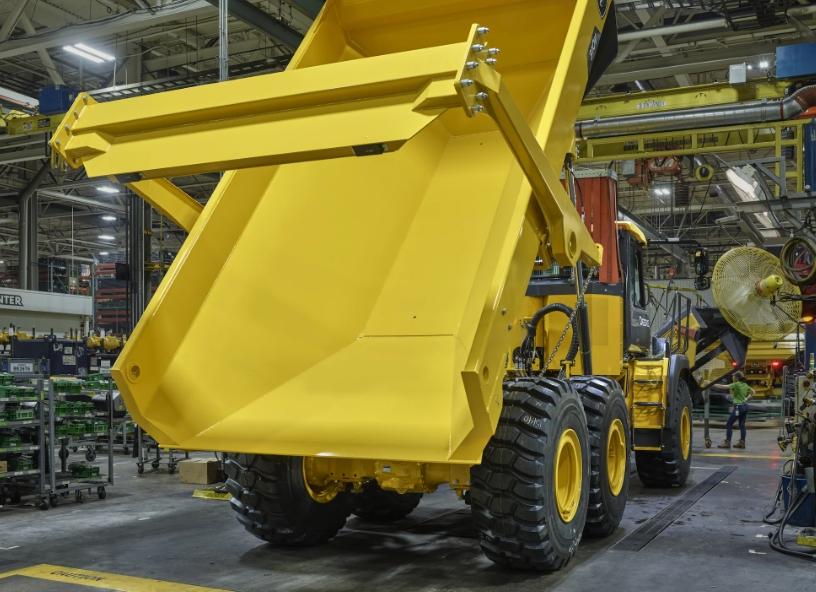 a yellow John Deere dump truck in a factory