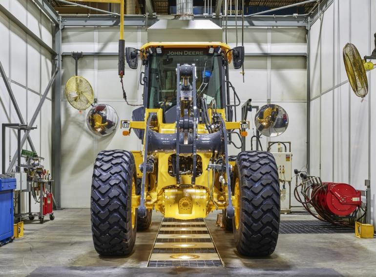 a John Deere wheel loader without a front bucket in a factory